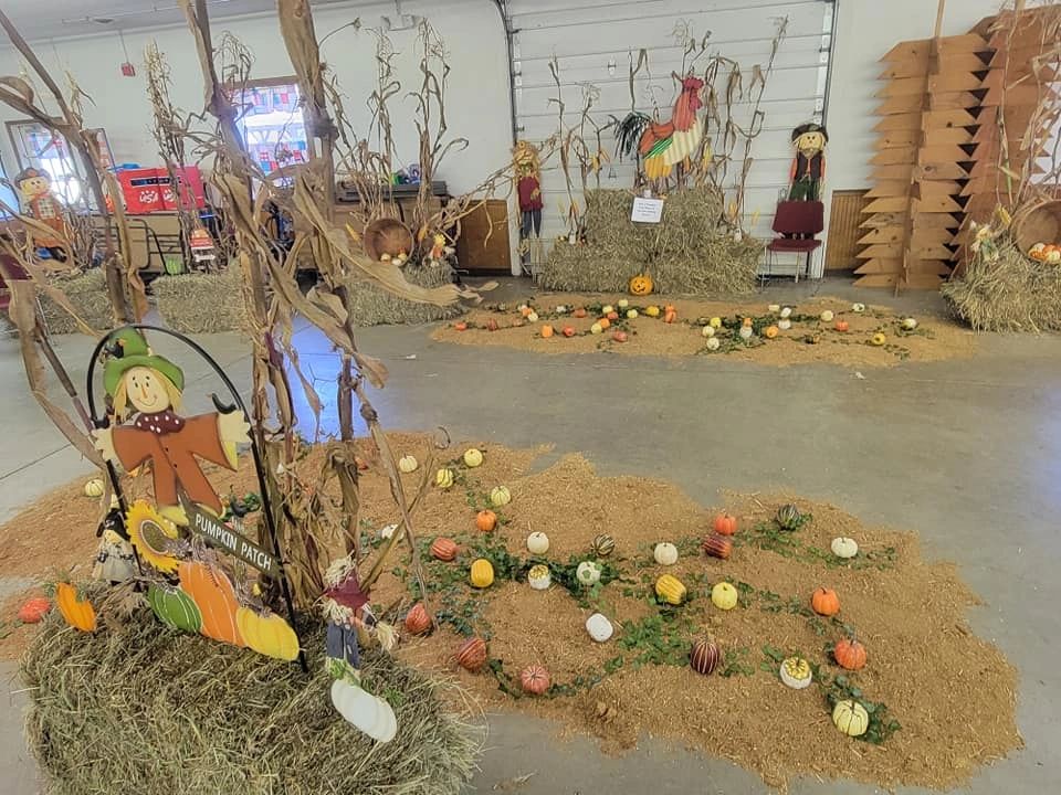 Fall-themed display with pumpkins, hay bales and scarecrow