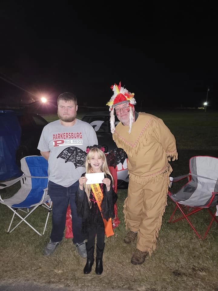 Three people in costumes posing outdoors at night